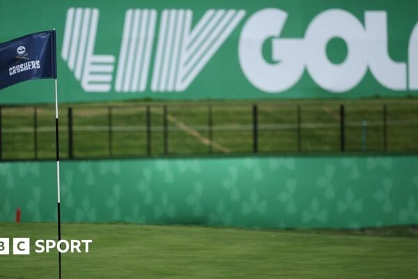 A flag on a golf course green in front of a sign that says 'LIV Golf'