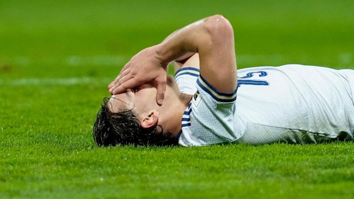 Pio Esposito lies on the pitch with his hands covering his face after missing a scoring chance.