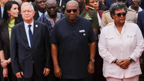Reuters Ghana's President John Dramani Mahama, Barbados' Prime Minister Mia Amor Mottley and other dignitaries stand looking solemn.
