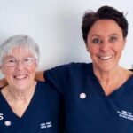 A care worker helps a woman down a flight of stairs