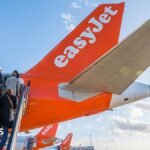 People climb steps onto an easyJet plane.
