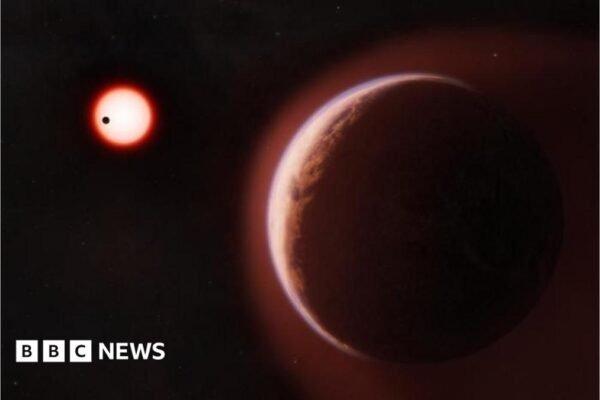 An artist's impression of exoplanet LHS 1140b, a large reddish-brown rocky planet filling the foreground, edged with a faint blue-white atmospheric glow. In the dark background, a small red star glows brightly, with a second, closer planet shown as a tiny black silhouette crossing in front of it