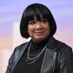 Diane Abbott sitting in the Sunday with Laura Kuenssberg TV studio, wearing a black leather jacket over a black top