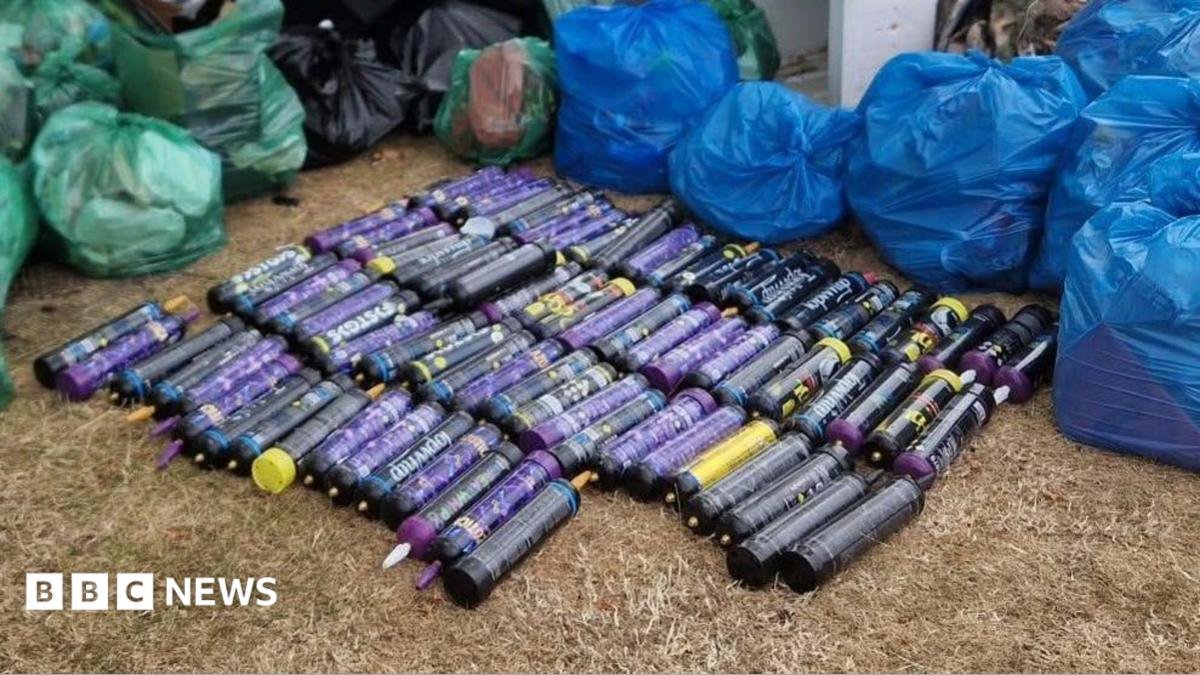 82 purple cylinder-shaped canisters on the grass. They are surrounded by green and blue plastic bags full of rubbish.