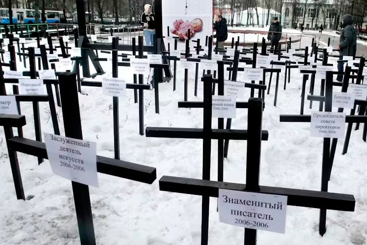 Rows of simple wooden crosses stand in snow.