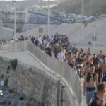 Dozens of migrants walking on a coastal path