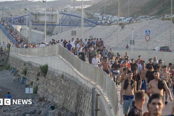 Dozens of migrants walking on a coastal path
