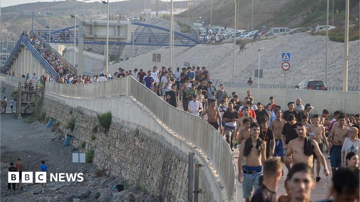 Dozens of migrants walking on a coastal path