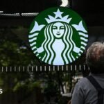 A cleaning lady wipes the window of a Starbucks coffee shop