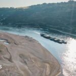An aerial view as a cargo ship passes a huge exposed sandbar on the Rhine River