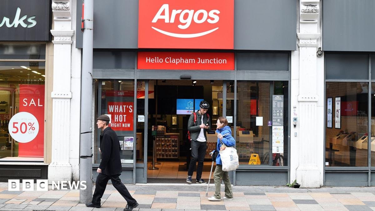 An Argos storefront in Clapham Junction. A young man is walking out of the shop while two people walk past it.