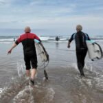 Men climbing wall by the sea
